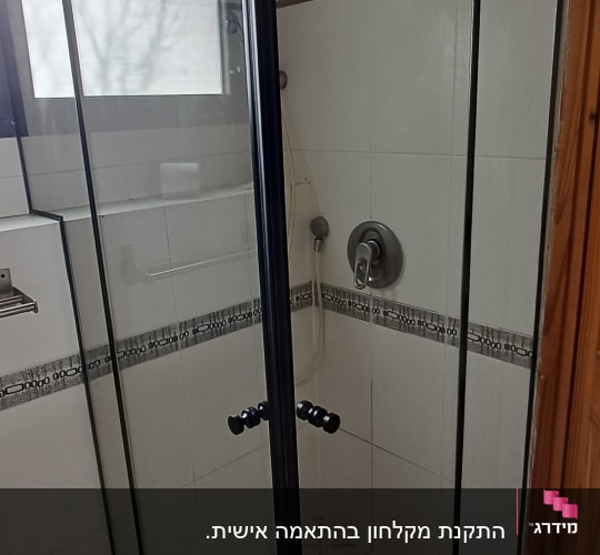 מקלחון זכוכית עם דלתות שחורות בחדר אמבטיה